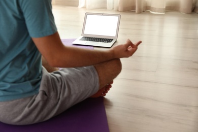Photo of Man practicing yoga while watching online class at home during coronavirus pandemic, closeup. Social distancing