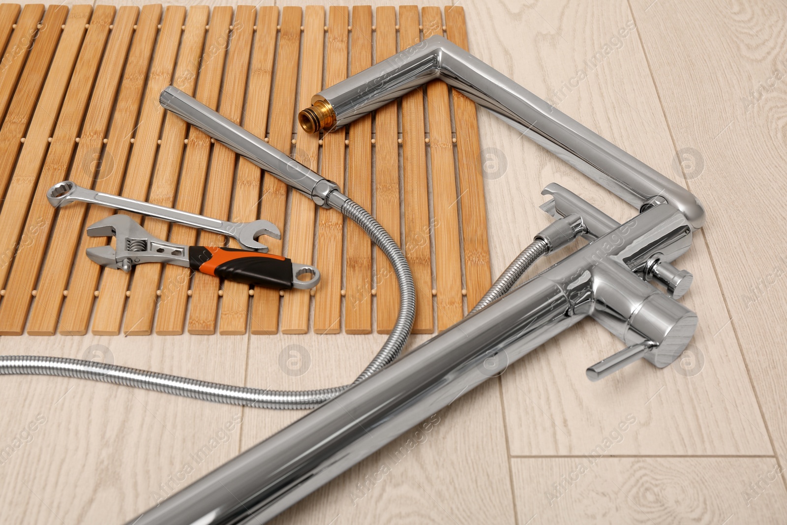 Photo of Professional plumbing tools and water tap on floor in bathroom