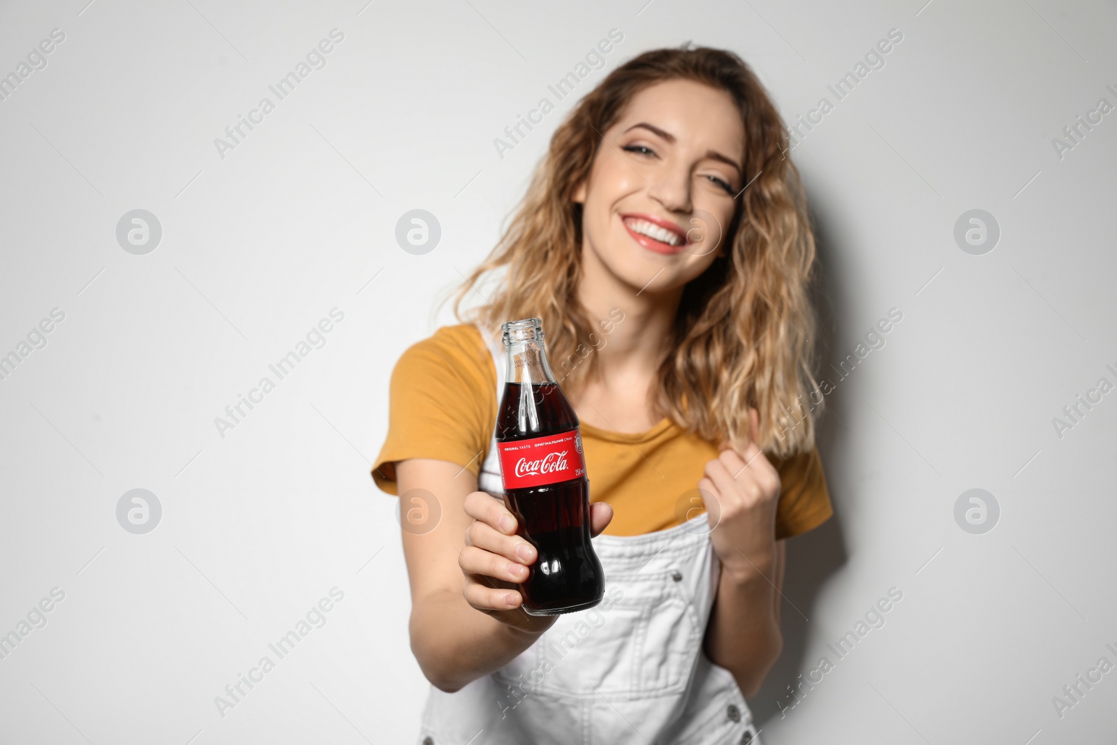 Photo of MYKOLAIV, UKRAINE - NOVEMBER 28, 2018: Young woman with bottle of Coca-Cola on white background