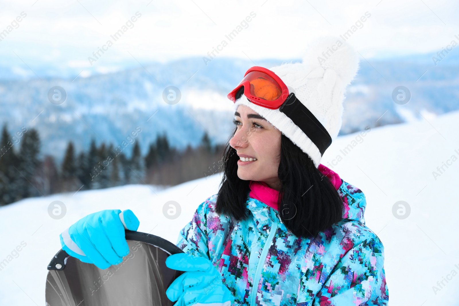 Photo of Young woman with snowboard at mountain resort. Winter vacation