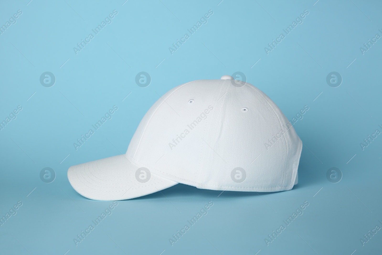 Photo of Stylish white baseball cap on light blue background