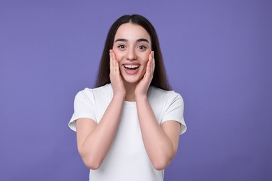 Portrait of happy surprised woman on violet background