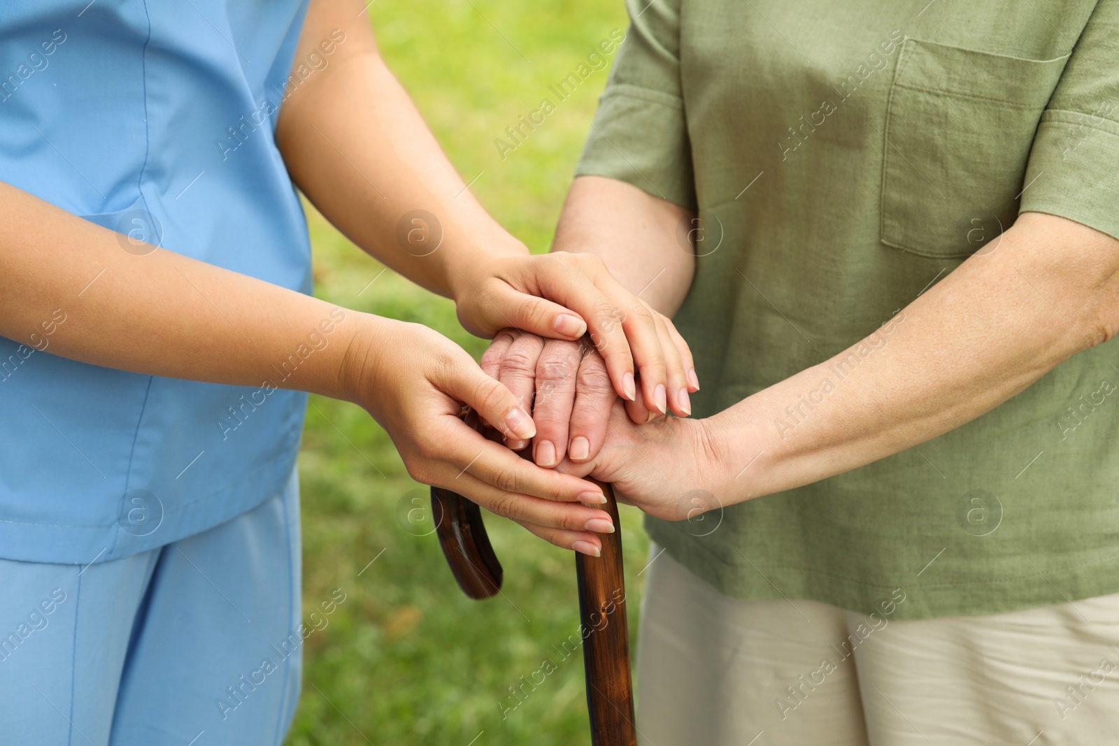 Photo of Elderly woman with walking cane and female caregiver outdoors, closeup