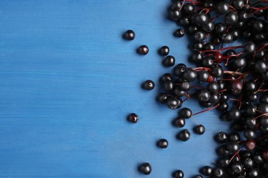 Ripe elderberries (Sambucus) on blue wooden table, flat lay. Space for text