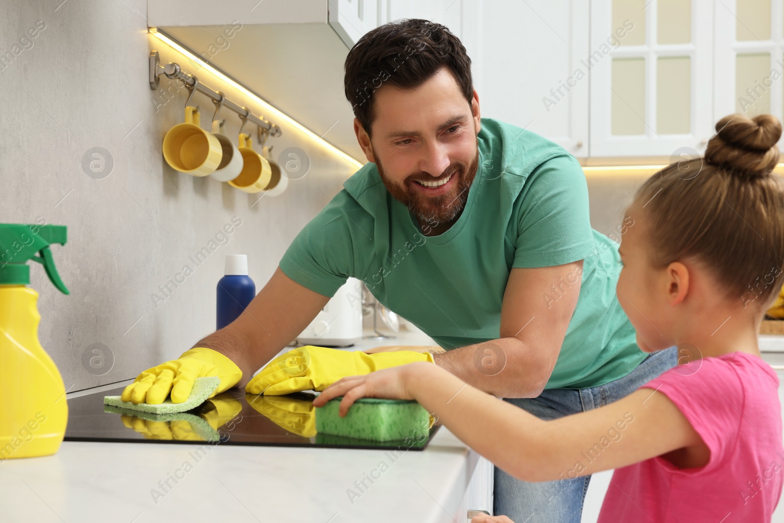 Photo of Spring cleaning. Father and daughter tidying up stove in kitchen together