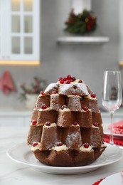 Delicious Pandoro Christmas tree cake decorated with powdered sugar and berries on white marble table