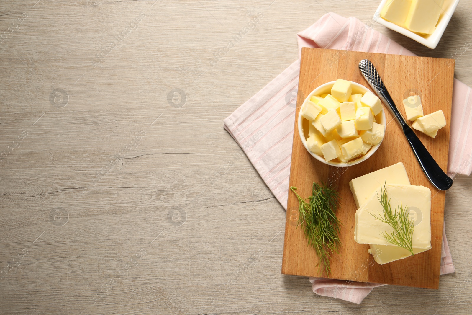 Photo of Tasty butter with dill and knife on wooden table, flat lay. Space for text