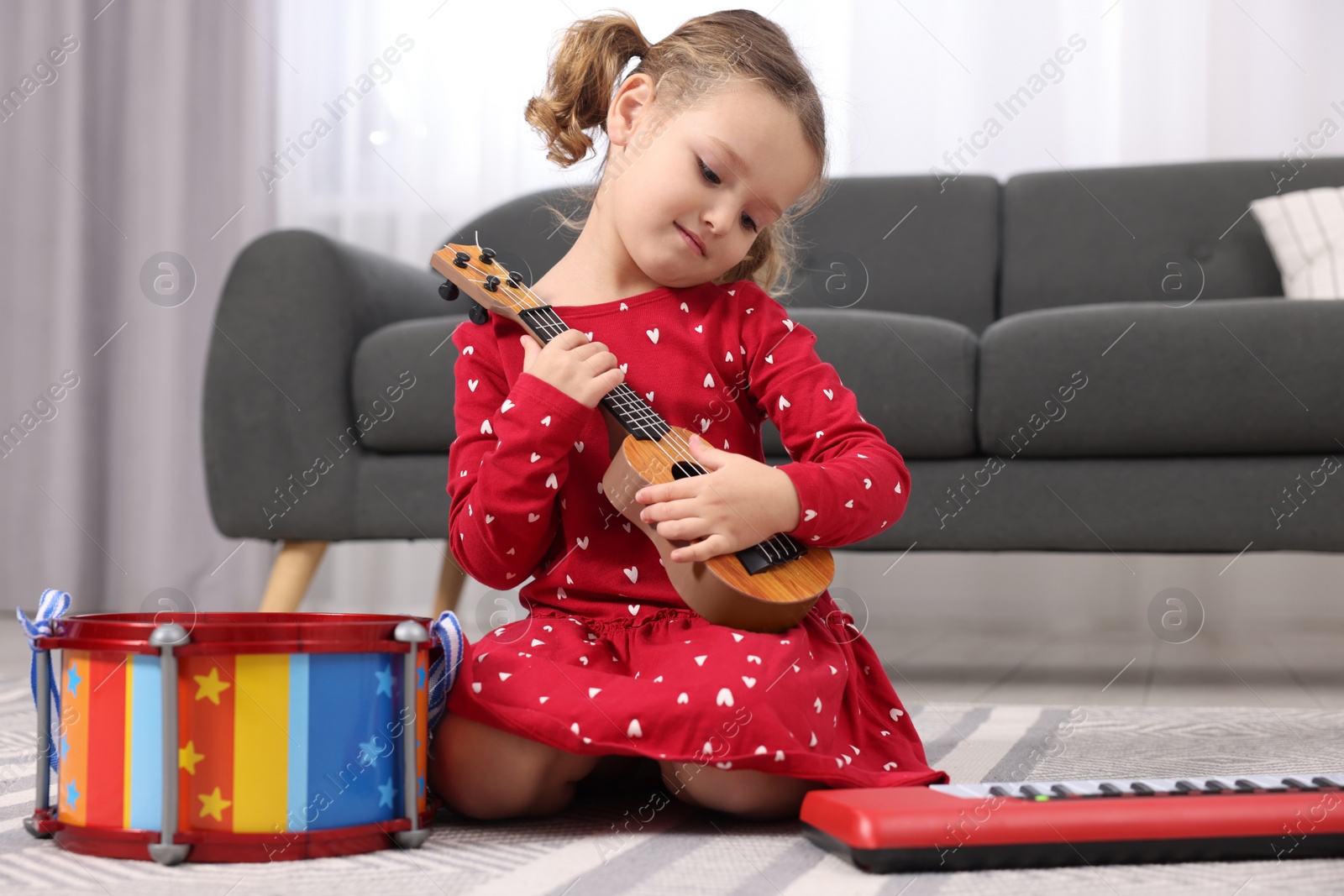 Photo of Little girl playing toy guitar at home