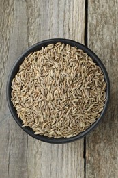 Bowl of caraway seeds on wooden table, top view