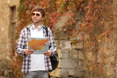 Traveler with world map near building outdoors