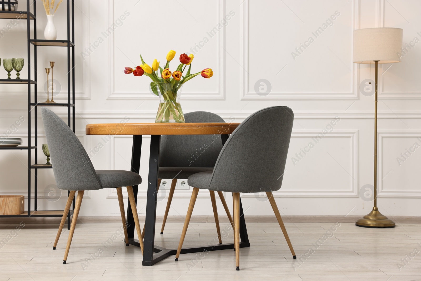 Photo of Stylish dining room interior with comfortable furniture and beautiful tulips