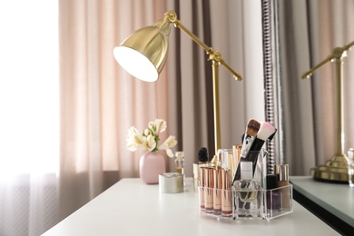 Photo of Luxury makeup products and accessories on dressing table with mirror. Space for text