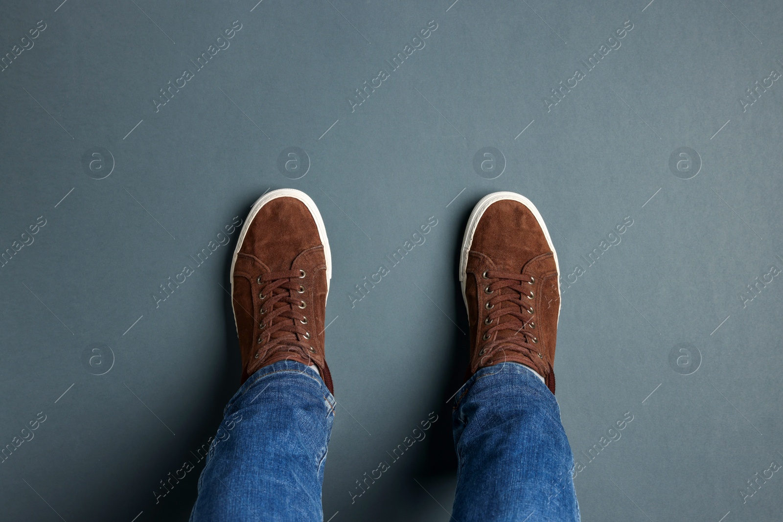 Photo of Man in stylish sneakers standing on grey background, top view