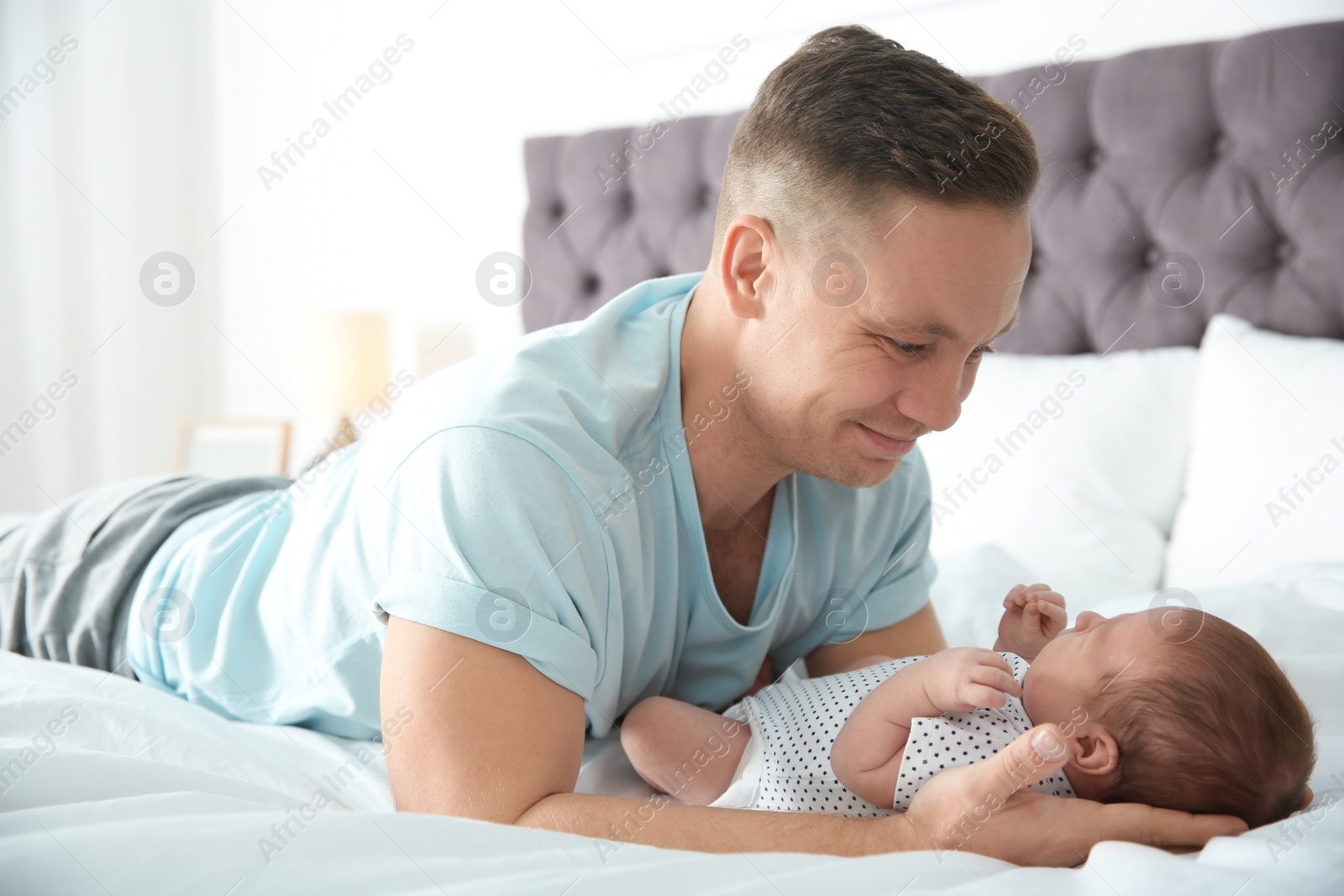 Photo of Man with his newborn baby on bed