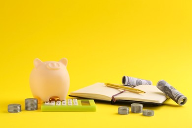 Financial savings. Piggy bank, money, calculator and stationery on yellow background
