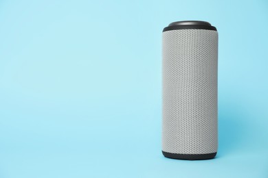 Photo of One portable bluetooth speaker on light blue background, space for text. Audio equipment
