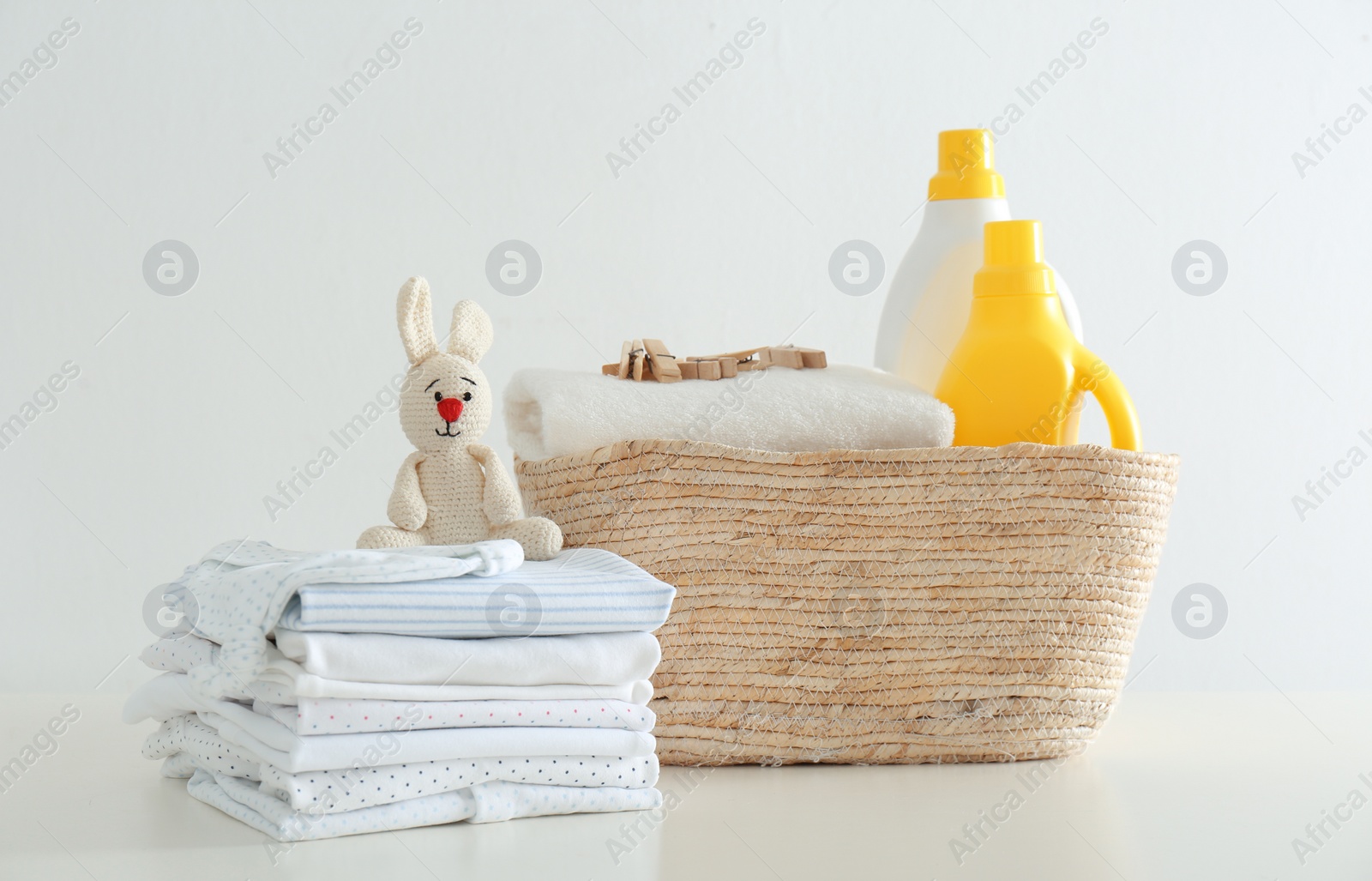 Photo of Fresh baby laundry and bottles of detergent on white background