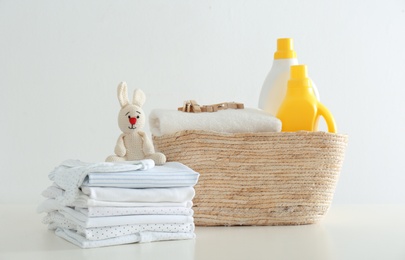 Fresh baby laundry and bottles of detergent on white background