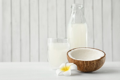 Composition with bottle and glass of coconut water on white wooden table. Space for text