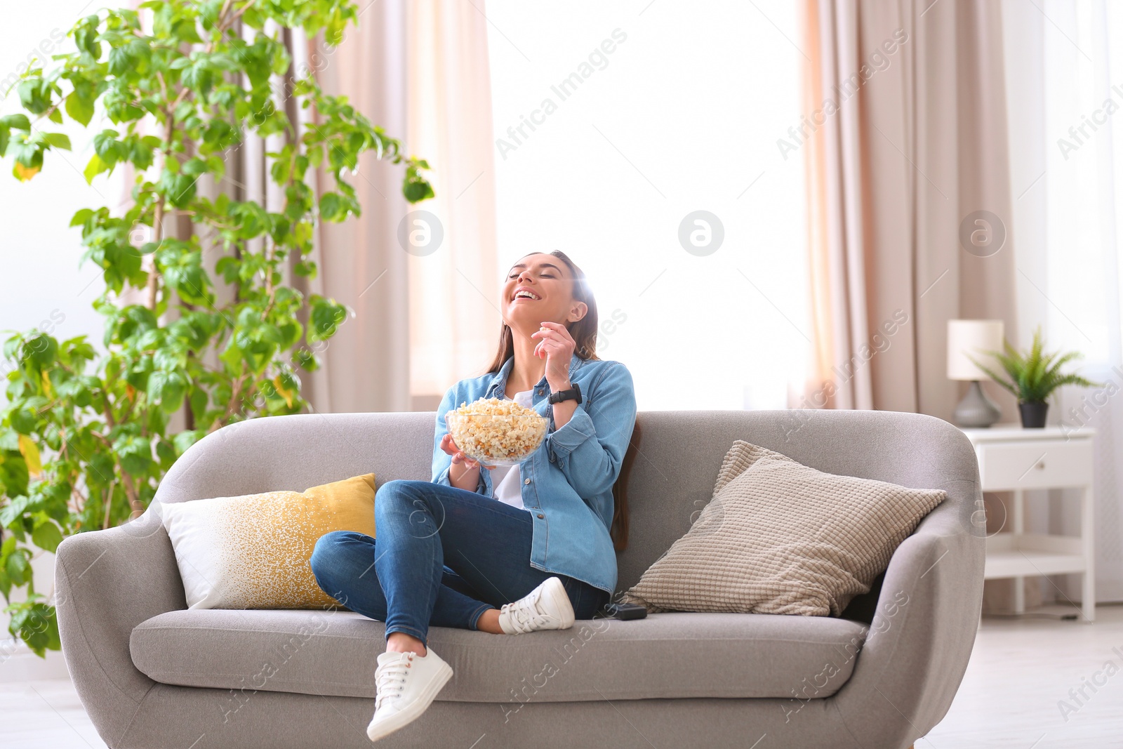Photo of Young woman watching movie with popcorn in living room