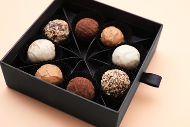 Photo of Box of tasty chocolate candies on beige background, closeup