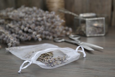 Scented sachet with dried lavender flowers on wooden table, closeup