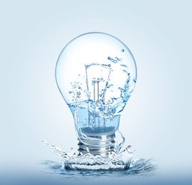 Image of Light bulb with water splashes on light background. Alternative energy source