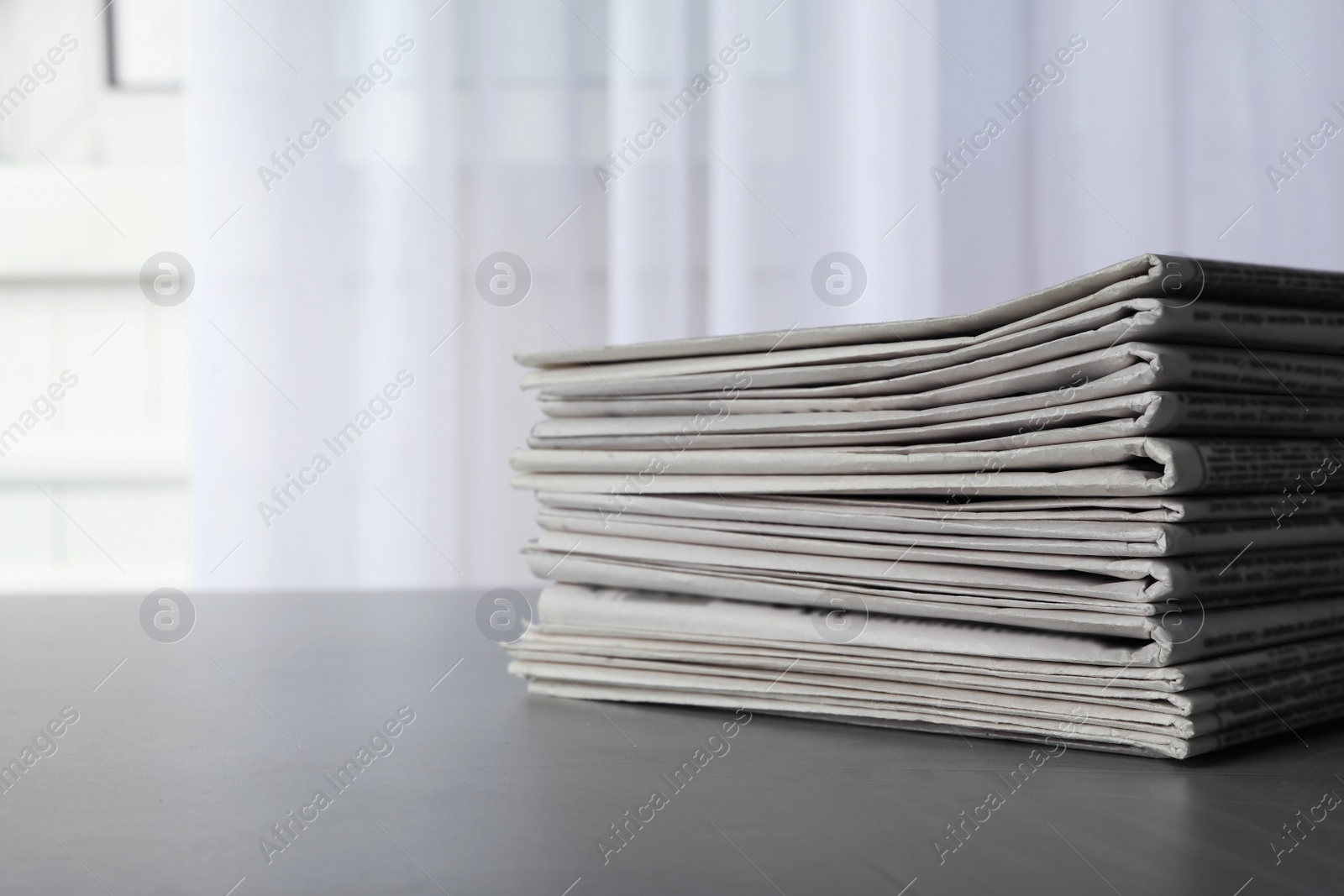 Photo of Stack of newspapers on grey table, space for text. Journalist's work