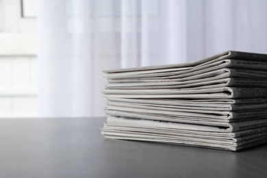 Photo of Stack of newspapers on grey table, space for text. Journalist's work