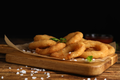 Photo of Delicious onion rings on wooden table, closeup