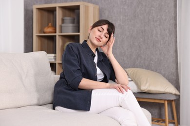 Photo of Beautiful young housewife on sofa at home