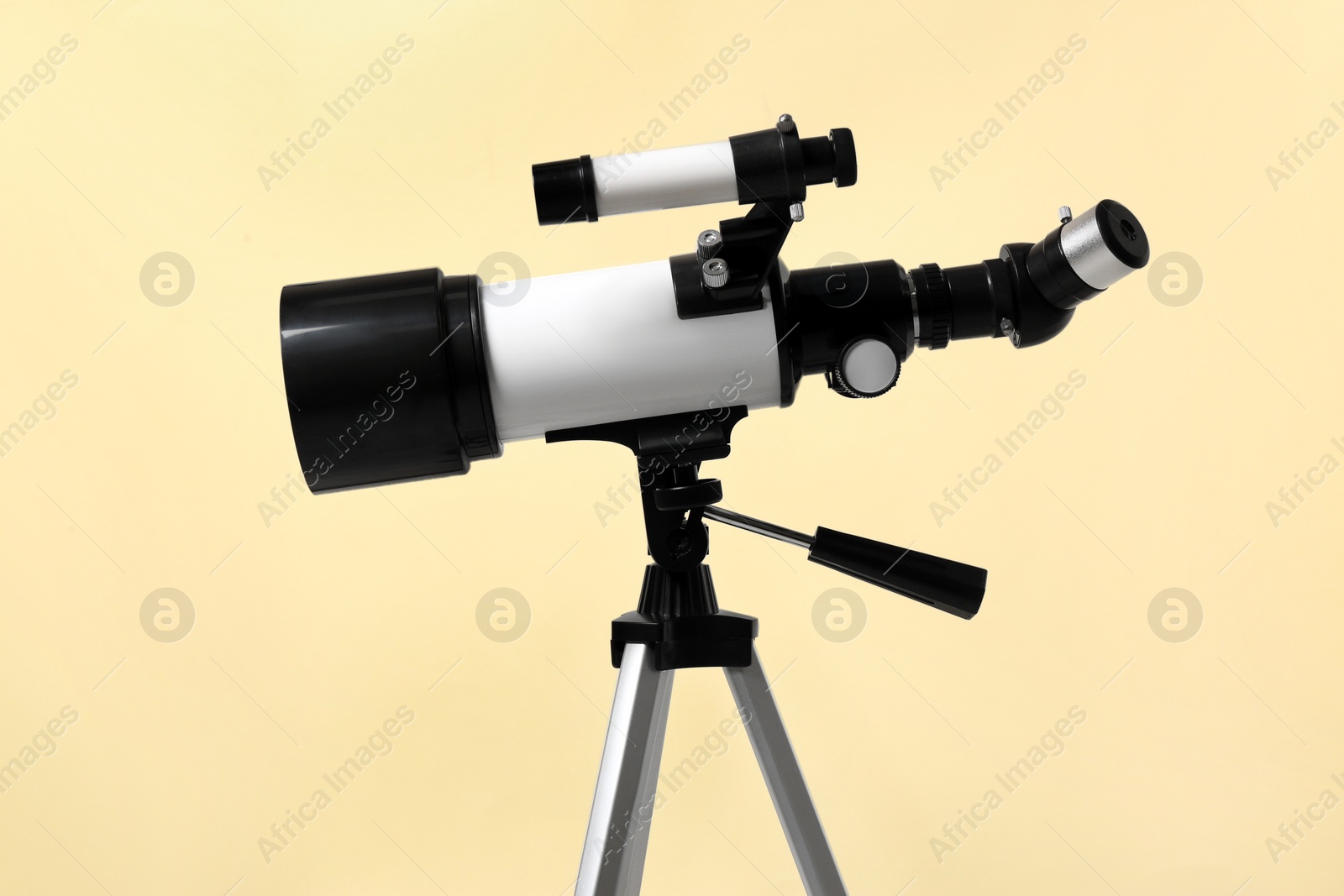 Photo of Tripod with modern telescope on beige background, closeup