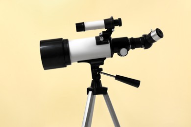 Photo of Tripod with modern telescope on beige background, closeup