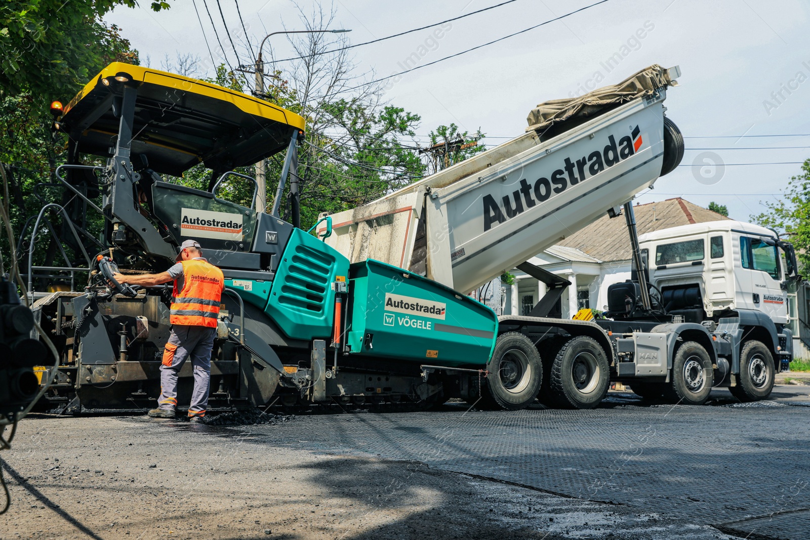 Photo of MYKOLAIV, UKRAINE - AUGUST 04, 2021: Worker with road repair machinery laying new asphalt