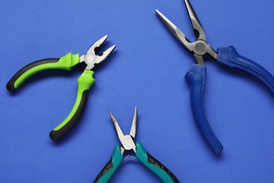Photo of Different pliers on blue background, flat lay