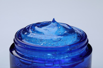 Photo of Jar of transparent cosmetic gel on light background, closeup