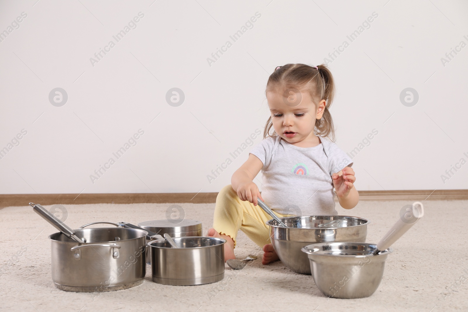 Photo of Cute little girl with cookware at home