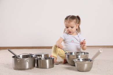 Photo of Cute little girl with cookware at home