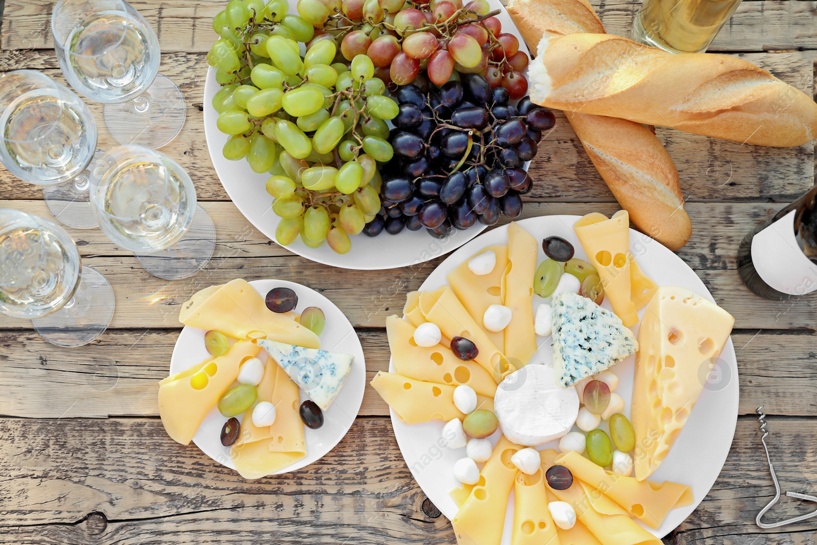 Photo of Wine, cheese and grapes on wooden table, top view. Vineyard picnic