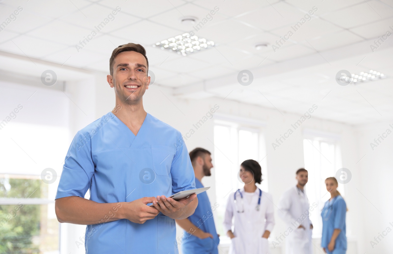 Photo of Male doctor in uniform with tablet at workplace