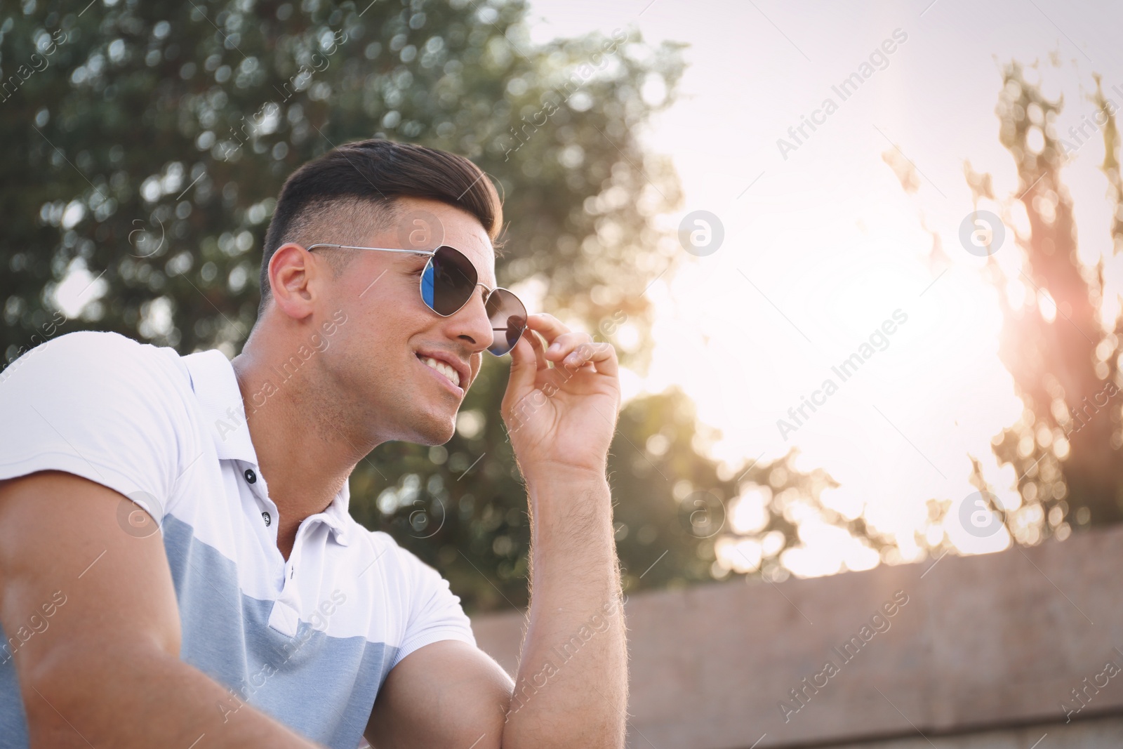 Photo of Handsome man wearing stylish sunglasses on city street. Space for text