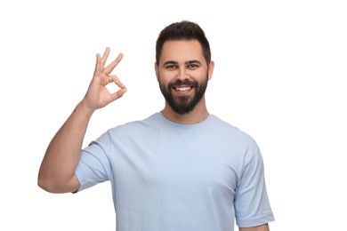 Photo of Man with clean teeth showing OK gesture on white background