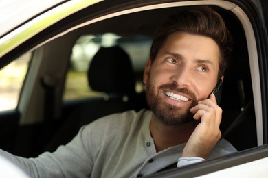 Photo of Happy bearded man talking on smartphone in car, view from outside