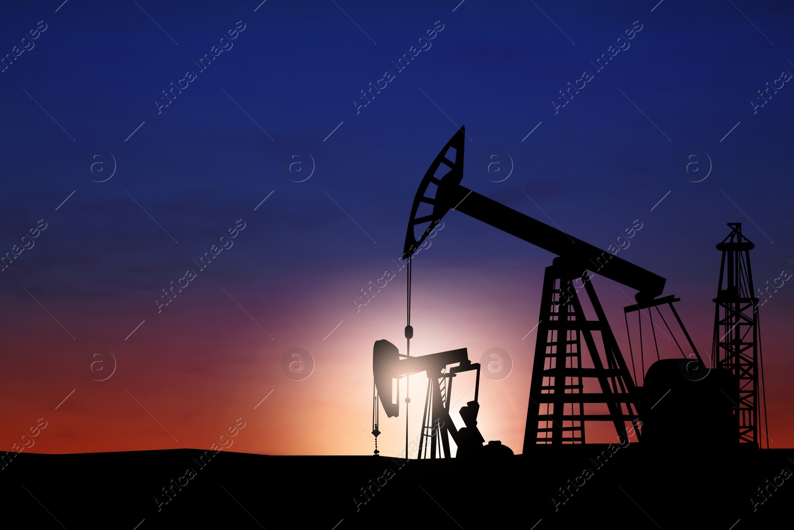 Image of Silhouettes of crude oil pumps at sunset. Space for text