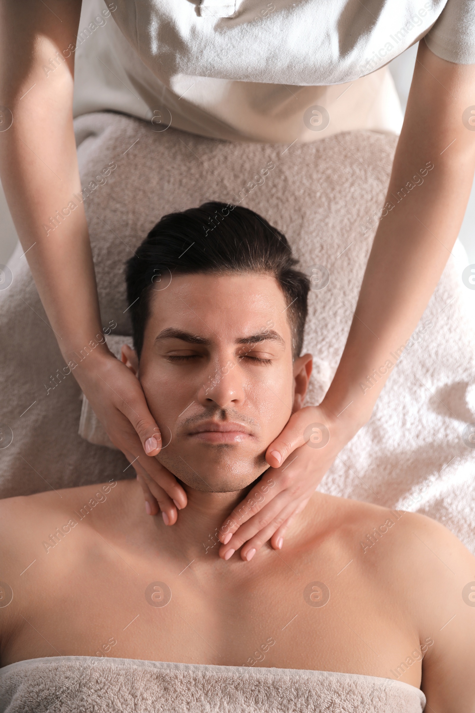 Photo of Man receiving facial massage in beauty salon, top view