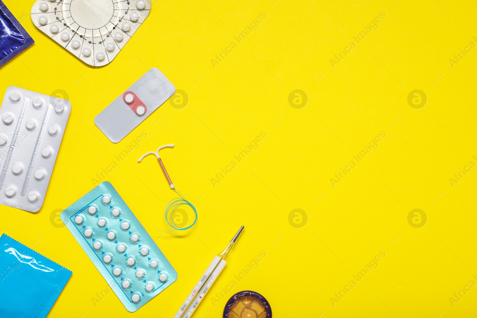 Photo of Contraceptive pills, condoms, intrauterine device and thermometer on yellow background, flat lay and space for text. Different birth control methods