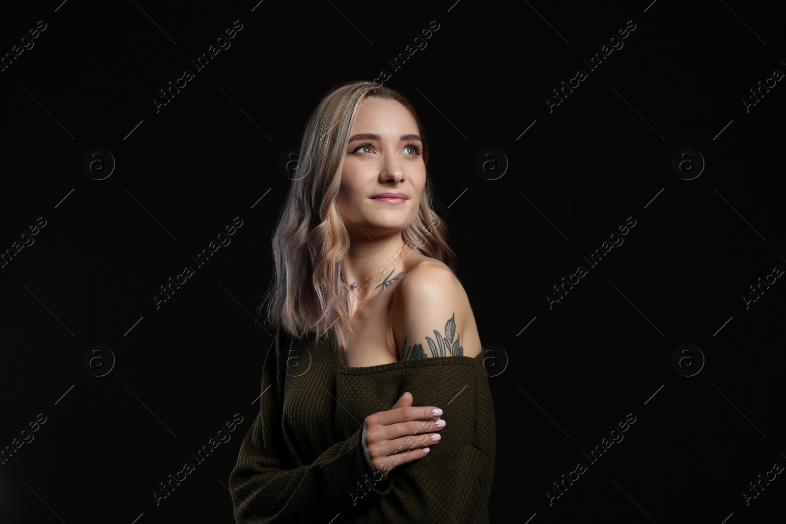 Photo of Beautiful woman with tattoos on body against black background