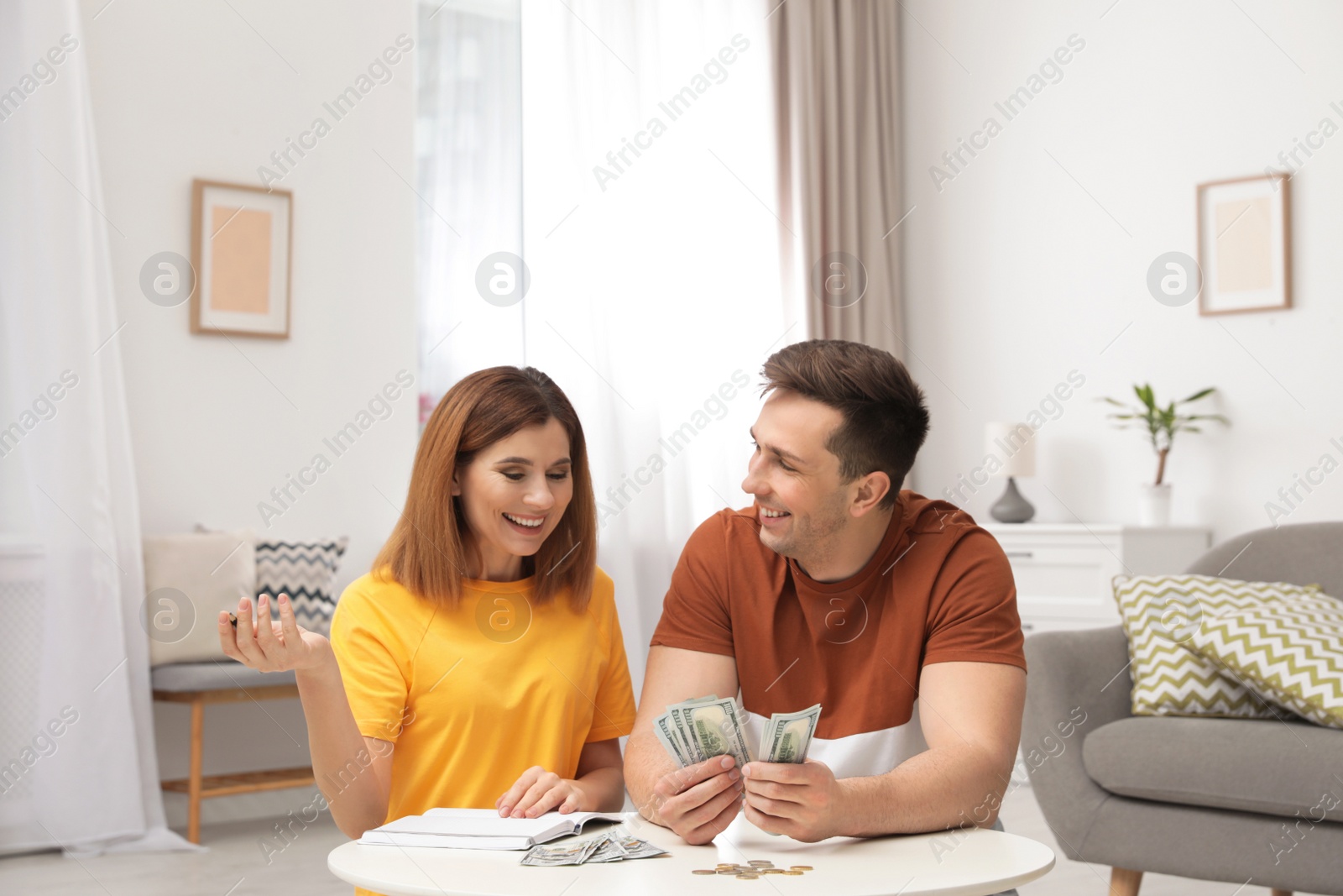 Photo of Couple counting money at table in living room