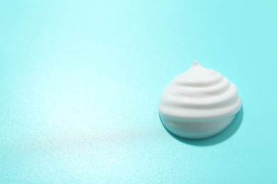 Drop of face cream on light blue background. Space for text