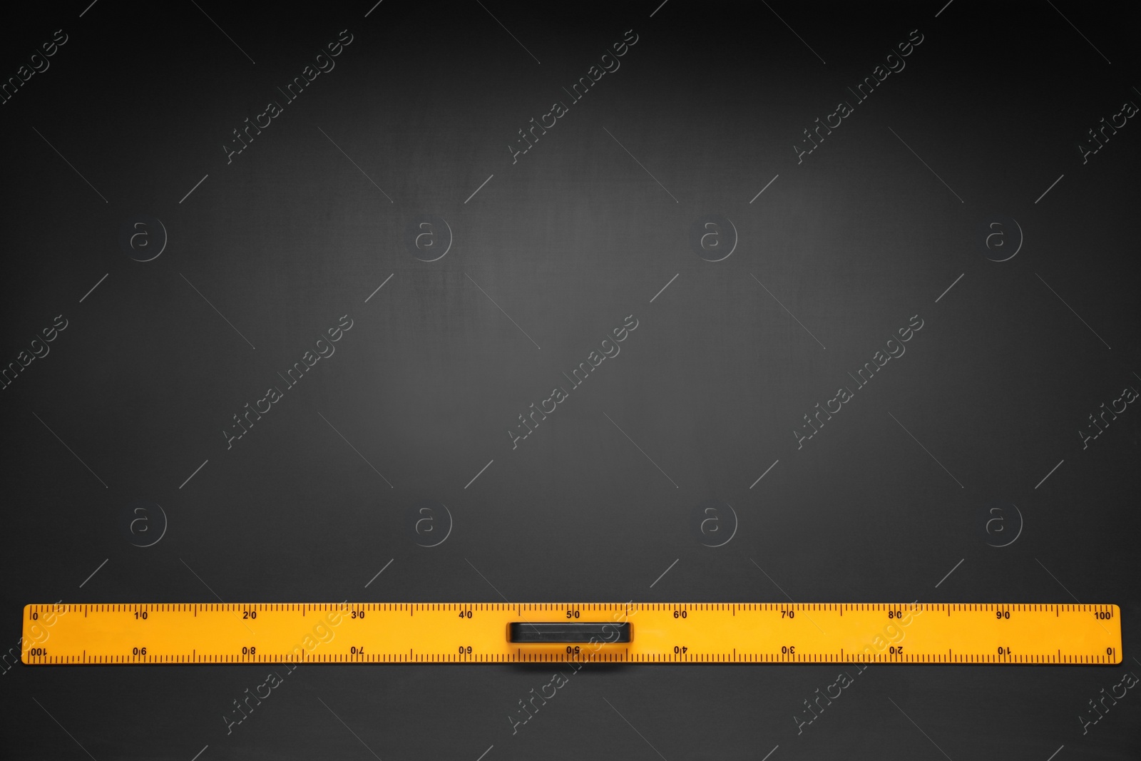 Photo of Yellow school ruler on blackboard, top view. Space for text